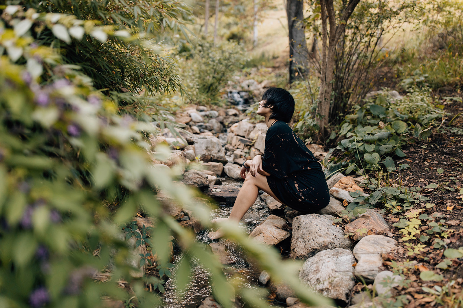 Kai Lum seated in a garden by a stream
