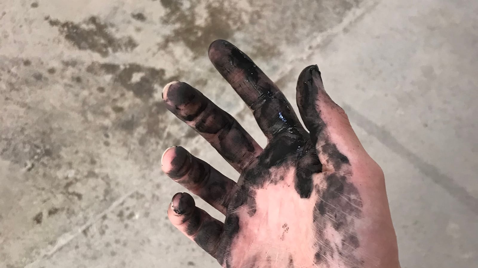 Kai Lum's hand, stained with black clay from the studio